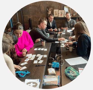 Group of learners taking part in a first aid training session around a table, using training cards