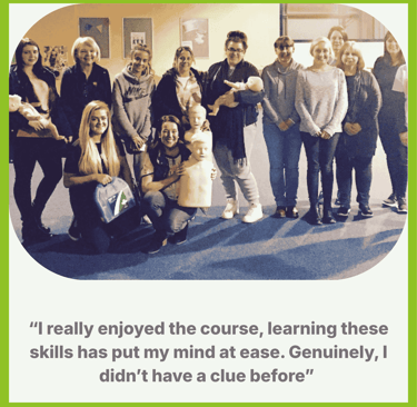 A group of learners at the end of their training session smiling and holding the training manikins 