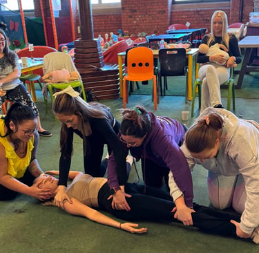 Group of learners practising first aid skills on a casualty during a practical training session