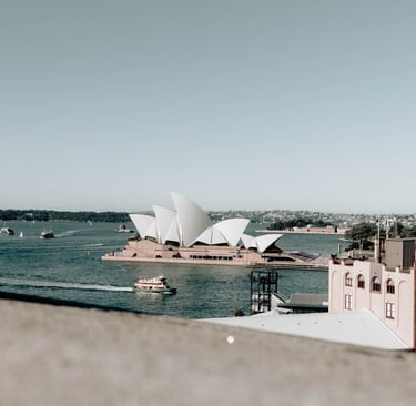 a view of a large building with a boat in the water. Opera House Sydney