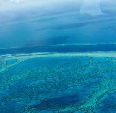 Aerial view of the turquoise Great Barrier Reef coral formations in the blue Pacific Ocean.