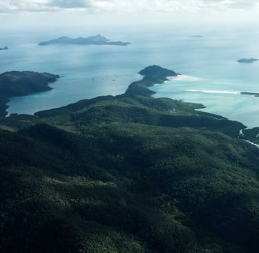 Aerial view of lush green Whitsunday Islands with turquoise water and white sand beaches.
