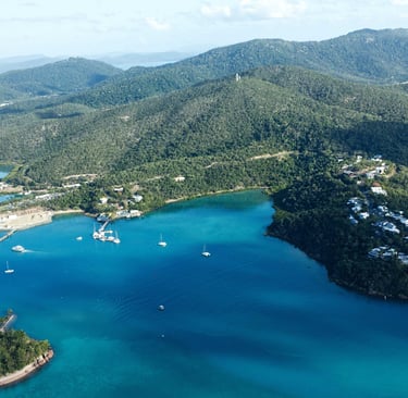 Aerial view of Hamilton Island with turquoise water, luxury resorts, and sailing yachts in the Whitsundays.