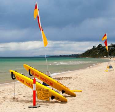 a surfboarder is sitting on the beach. Australina surf rescue beach
