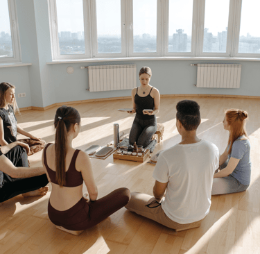 Groupe of five employees sitting in circle on the floor, in a corporate setting, with an instructor.