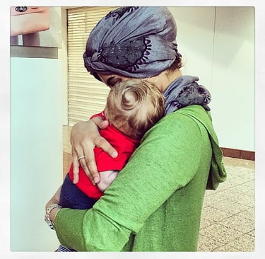 A picture of a Muslim woman holding a baby boy.