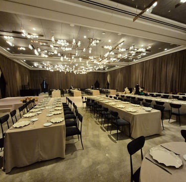 Luxury event setup featuring long dining tables, neutral linens and black seating