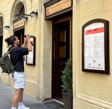 Turista fotografiando la entrada y el menú exterior del restaurante Hungarikum Bisztró en Budapest, 