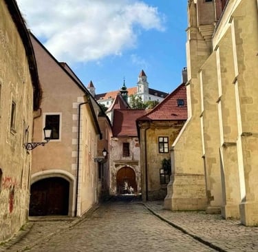 Calle adoquinada del casco antiguo de Bratislava, con fachadas históricas, vista del castillo