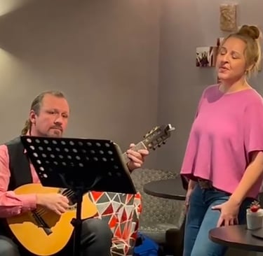 Sängerin mit pinkem Oberteil und ein Gitarrist mit akustischer Gitarre und einem Notenständer