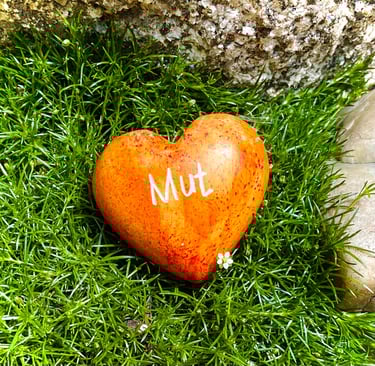 ein Herz mit der Aufschrift "Mut" liegt im Gras