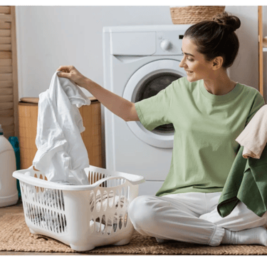 a woman sitting on the floor in front of a washing machine