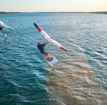 Saulėlydis Svencelėje su wing foil sportininku virš vandens paviršiaus