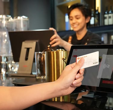 a person holding a credit card in front of a POS terminal