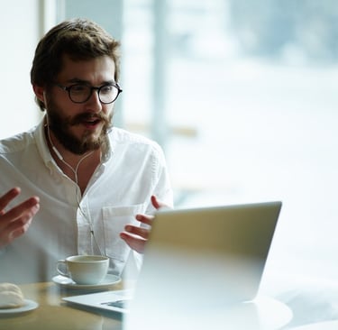 a man sitting at a table with a laptop and a cup of coffee