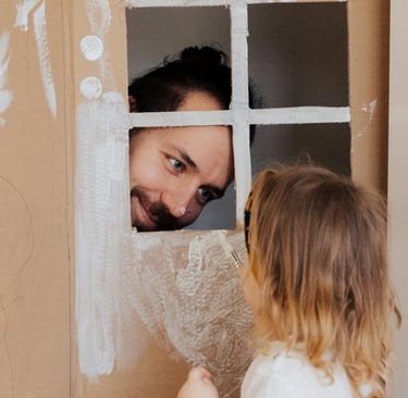 a man and a little girl playing with cardboard boxes