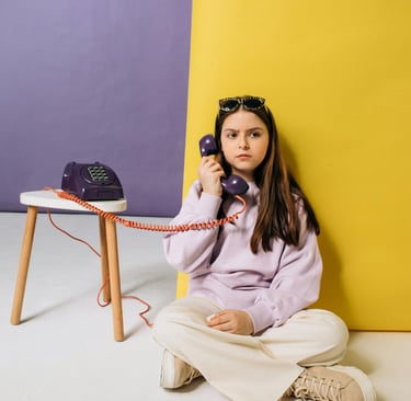 Photo d'une adolescente assise qui tient le combiné d'un téléphone du XXe siècle
