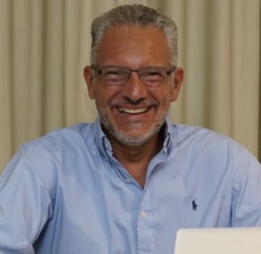 a man in a blue shirt and glasses sitting at a table