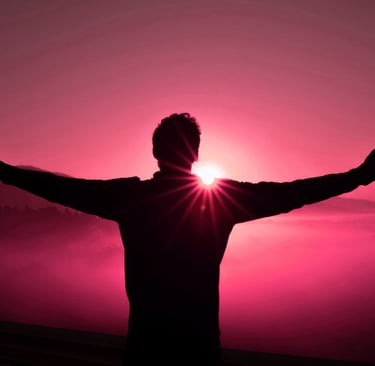 A man stretches his arms wide in the glow of a setting sun