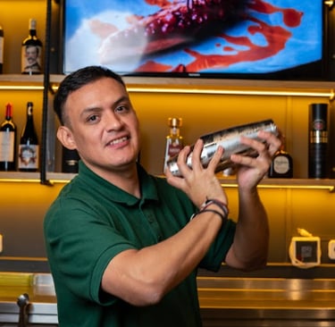 Camarero preparando cóctel en barra de restaurante, ambiente acogedor y profesional.