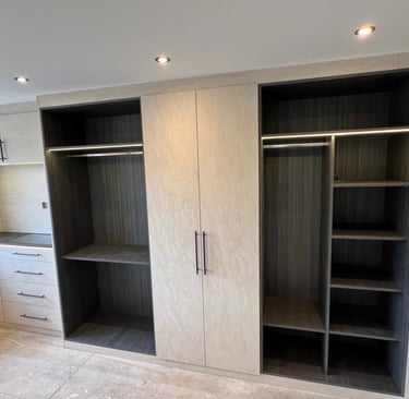 Custom built-in modern walk-in closet with integrated LED lighting, textured cream doors, and dark wood shelving.