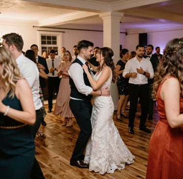 Guests enjoying a birthday party, dancing and smiling as DJ Cezaris controls the music from his setup.