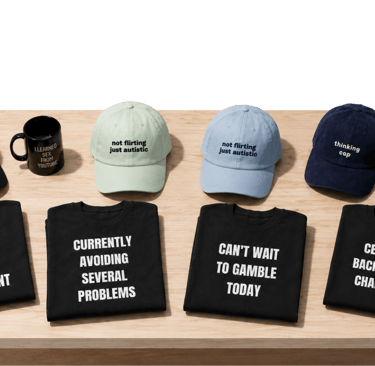 Collection of novelty graphic t-shirts, embroidered baseball caps, and mugs with funny slogans on a wooden table.