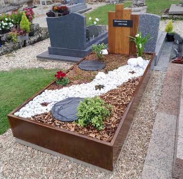 Monument funéraire moderne en métal et bois avec paillage d'écorces et rivière de galets blancs