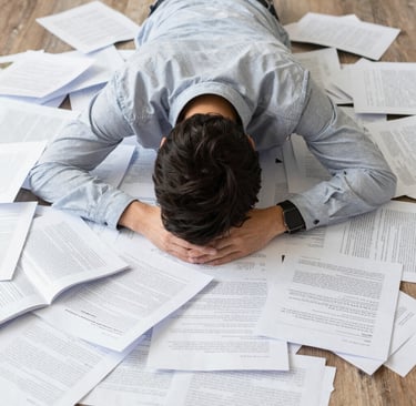 A fustrated entrepreneur burying his face in a mess of spreadsheeets