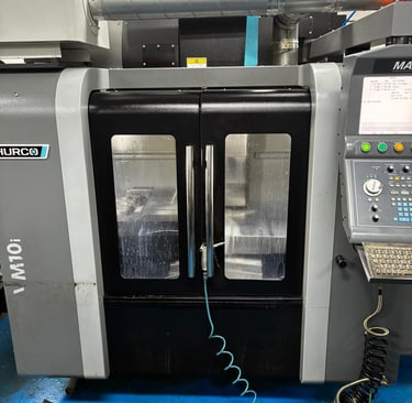 A Hurco VM10i CNC vertical machining center featuring a control panel and sliding safety doors.