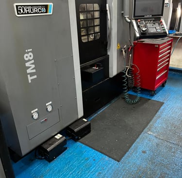 A Hurco TM8i CNC lathe machine in a workshop with a red tool chest and digital control panel.