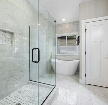 Casa de banho moderna com banheira, revestimento em porcelanato nas paredes e duche de vidro.