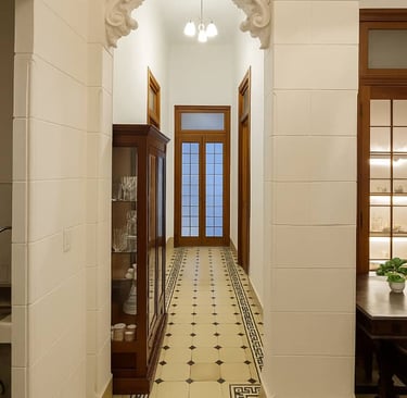 Elegant hallway featuring historic pattern floor tiles, arched white walls, and wood furniture.