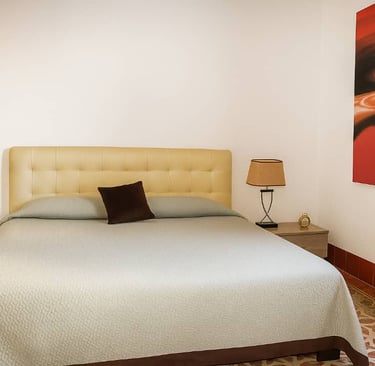 Modern bedroom with a double bed, beige tufted headboard, and bedside lamps on wooden nightstands.