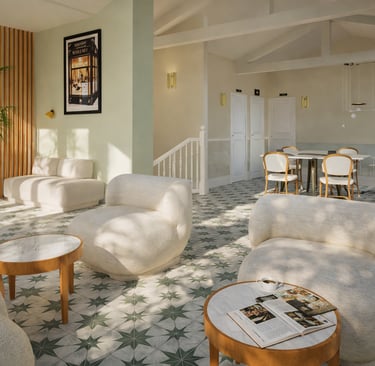 Modern hotel lobby featuring white bouclé lounge chairs, marble tables, and patterned tile flooring.