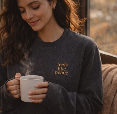 Frau mit Charcoal Heather Sweatshirt „feels like peace“ mit goldener Stickerei von Heartful Apparel