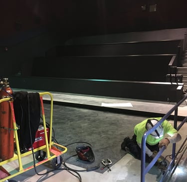 Installing powder coated movie theatre handrails Rick fabricated for Cinemark