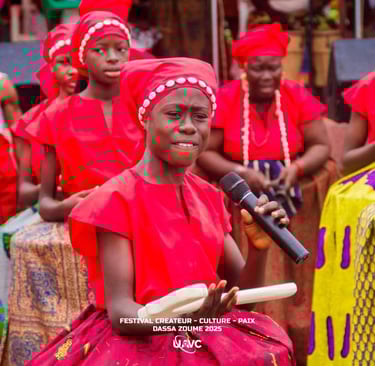 Young Benin singer performing in red traditional attire at the Dassa Zoume 2025 cultural festival.