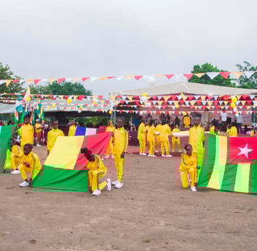 Students in yellow tracksuits hold flags of African nations during an outdoor cultural festival ceremony.