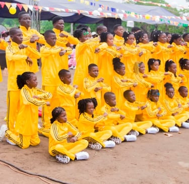 A youth dance troupe wearing matching yellow tracksuits performs a synchronized routine at an outdoor festival.