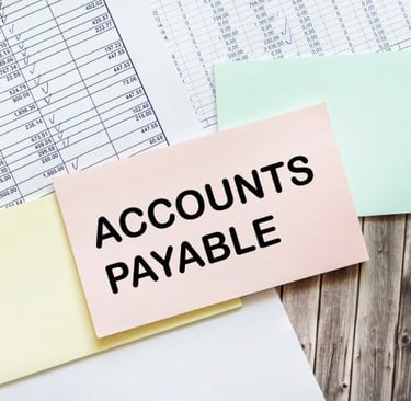 A sticky note that says `` accounts payable '' is sitting on top of a pile of papers.