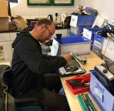 A Tech-Takeback technician works on a donated laptop