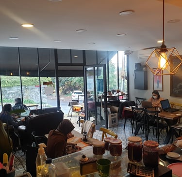 masalarda çalışan insanların bir şeyler yiyip içtiği bir kafe