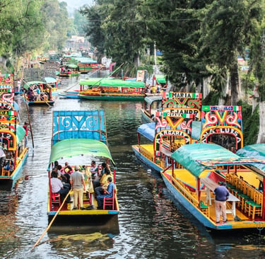 Colorful trajinera boats with tourists navigating the historic canals of Xochimilco in Mexico City.