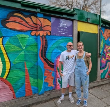 Two people outside 25th ALlerton Hut after painting a beautiful mural.