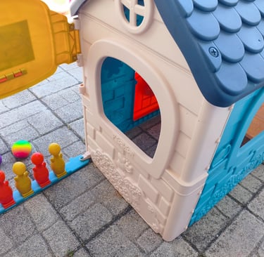 Review de casinha de plástico Feber mostrando o espaço interno e pinos de bowling no chão do pátio.