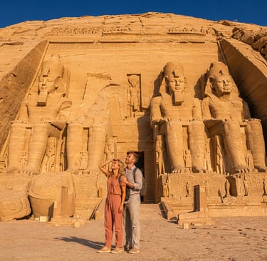 Couple admiring the colossal statues of Ramses II at the historic Abu Simbel Temple in Egypt.