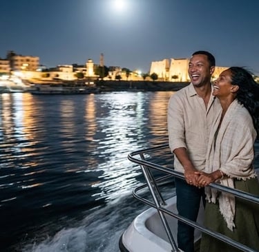 A happy couple on a luxury boat cruise on the Nile River at night with Luxor city lights and moon.