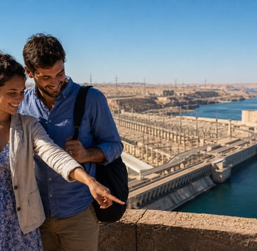 A smiling couple looking at the Aswan High Dam and Lake Nasser during a sunny day trip in Egypt.
