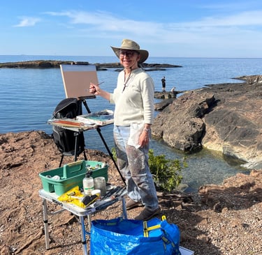 A photo of Margaret Moss, painting at Presque Isle Park in Maquette, Michigan.